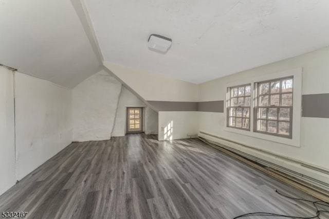 additional living space with a baseboard heating unit, vaulted ceiling, and dark wood-type flooring