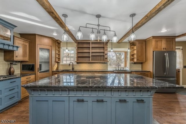 kitchen with appliances with stainless steel finishes, pendant lighting, beamed ceiling, and a spacious island