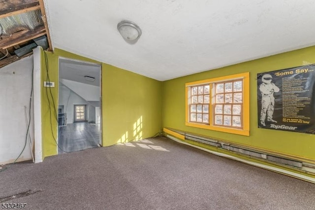 carpeted spare room featuring a baseboard heating unit and vaulted ceiling