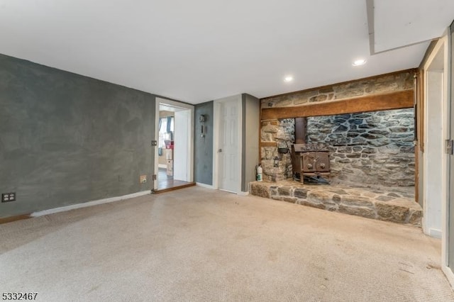 unfurnished living room with a wood stove and carpet