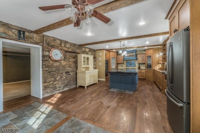 kitchen with decorative light fixtures, beamed ceiling, stainless steel fridge, a kitchen island, and dark wood-type flooring