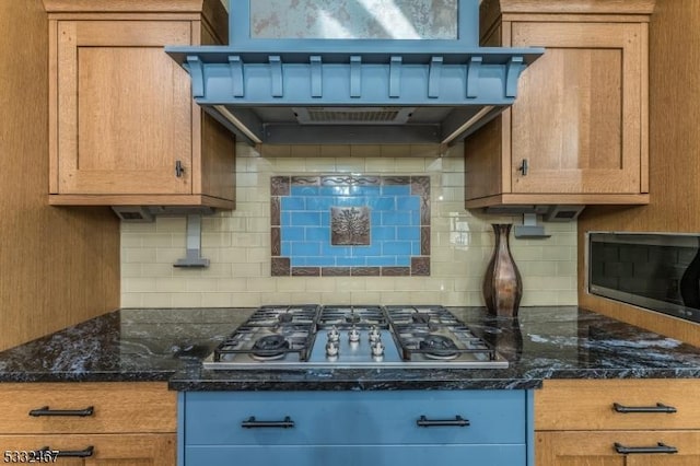 kitchen featuring appliances with stainless steel finishes, dark stone countertops, ventilation hood, and decorative backsplash