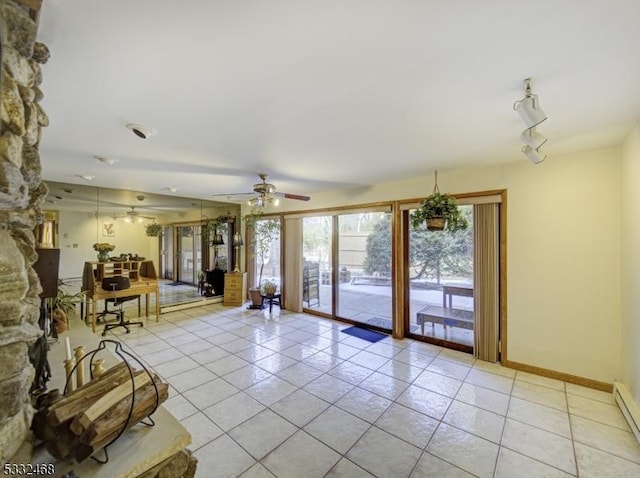 unfurnished living room with a baseboard heating unit, ceiling fan, light tile patterned flooring, and baseboards