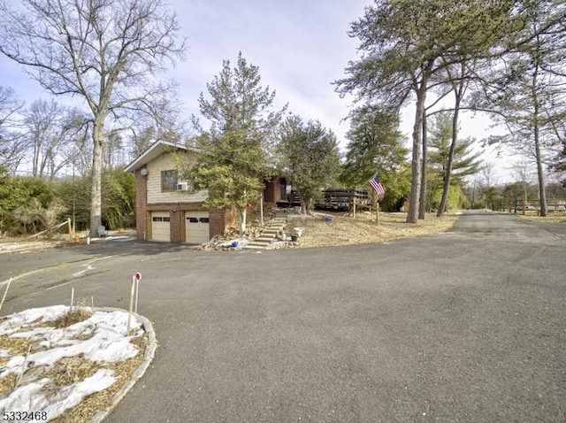 view of front of house featuring brick siding, driveway, stairway, and an attached garage