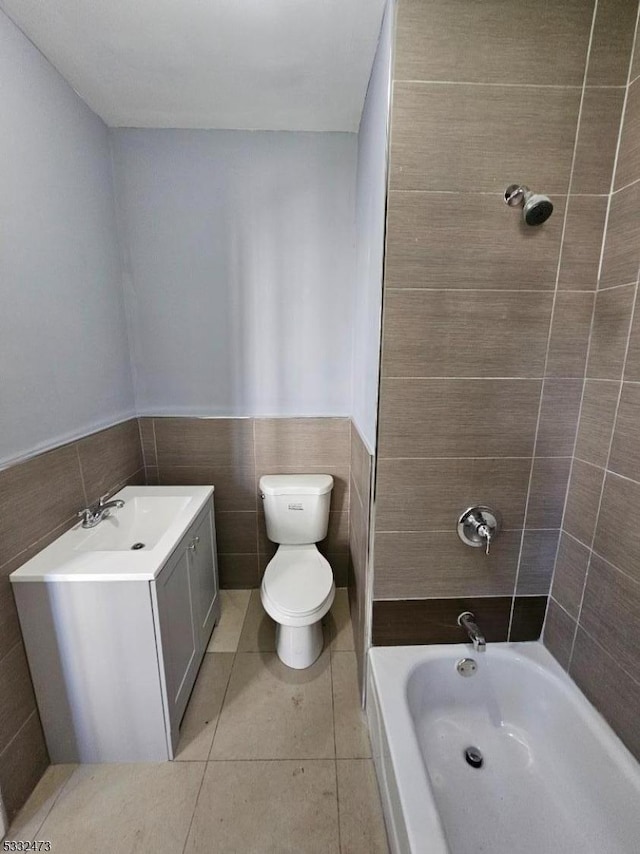 bathroom with tile patterned floors, vanity, toilet, and tile walls