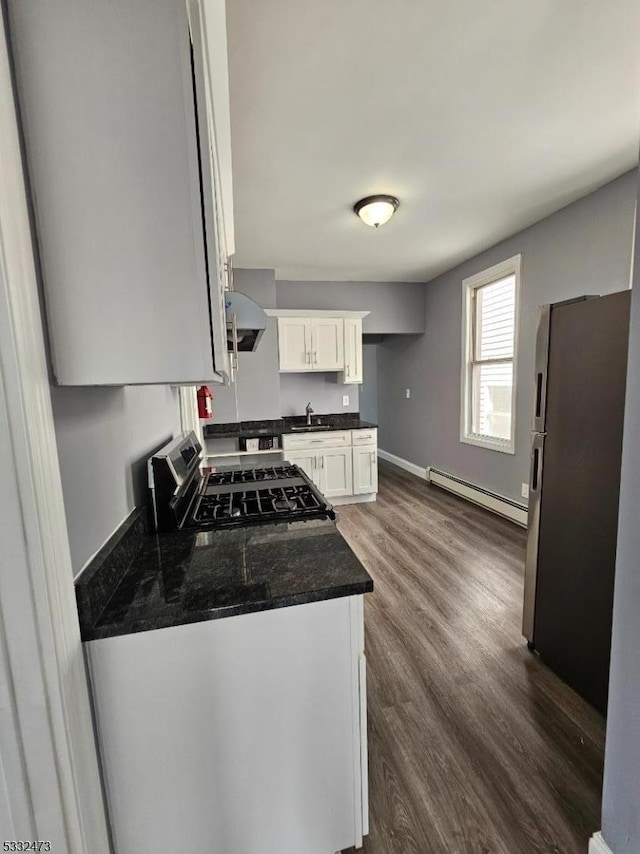 kitchen with appliances with stainless steel finishes, a baseboard heating unit, sink, white cabinets, and dark hardwood / wood-style floors