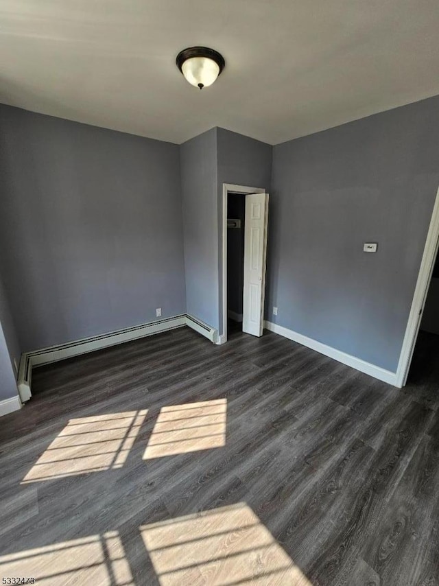 empty room with dark hardwood / wood-style floors and a baseboard radiator