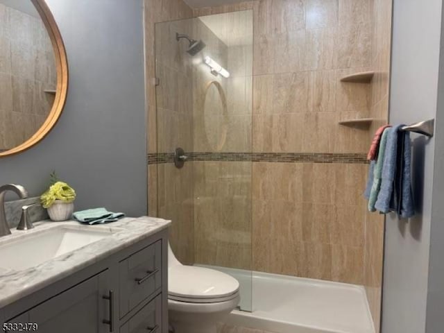 bathroom featuring toilet, a tile shower, and vanity