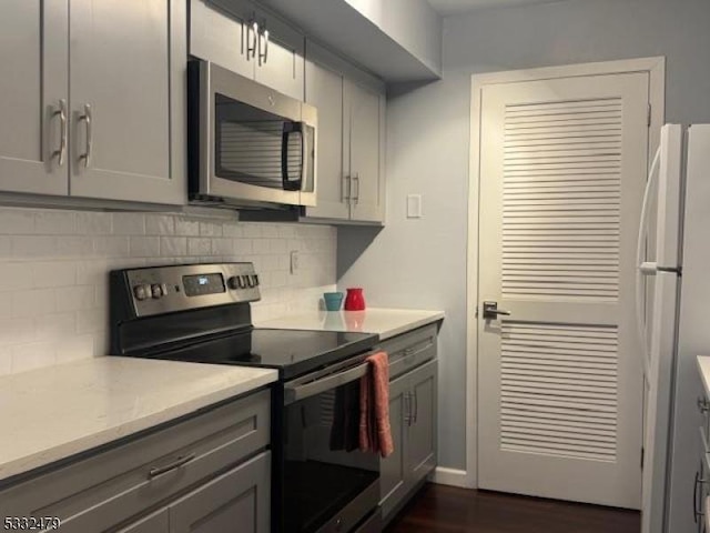 kitchen featuring appliances with stainless steel finishes, decorative backsplash, and gray cabinets