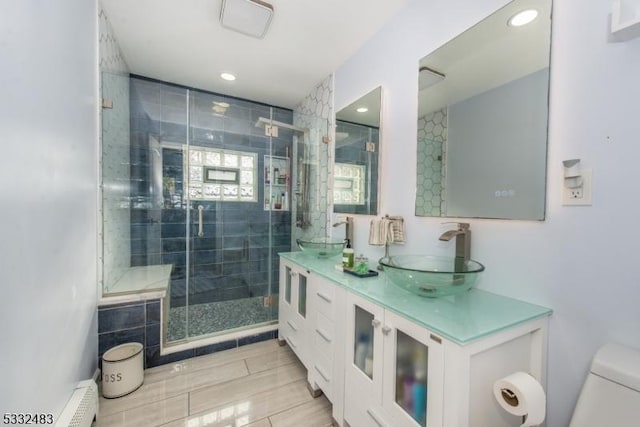 bathroom featuring vanity, toilet, a shower with door, and baseboard heating