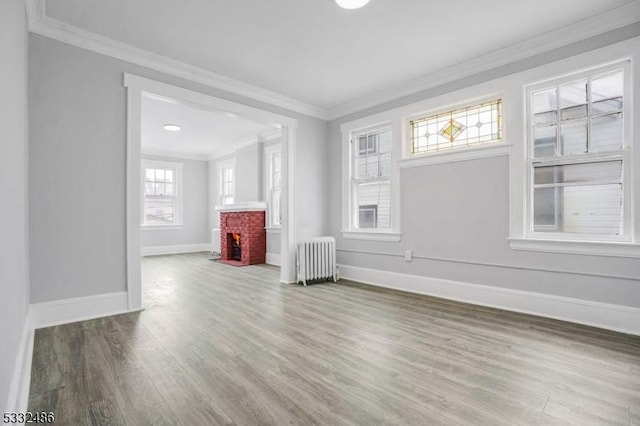 unfurnished living room with radiator heating unit, a healthy amount of sunlight, and ornamental molding