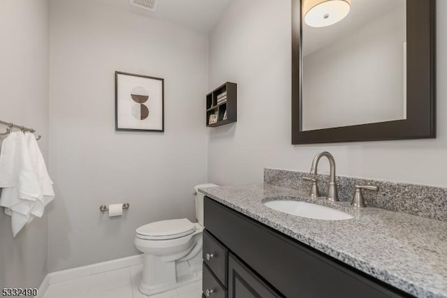 bathroom with toilet, vanity, and tile patterned flooring