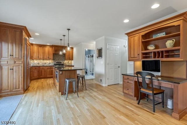 kitchen with a kitchen island, decorative light fixtures, ornamental molding, light wood-type flooring, and a breakfast bar