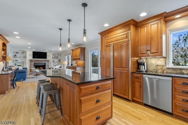 kitchen with dishwasher, a center island, decorative light fixtures, a fireplace, and light hardwood / wood-style flooring