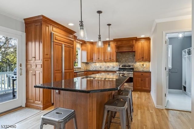 kitchen featuring hanging light fixtures, a kitchen bar, stainless steel gas range oven, and a center island