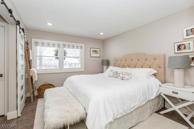 bedroom featuring a barn door and hardwood / wood-style flooring