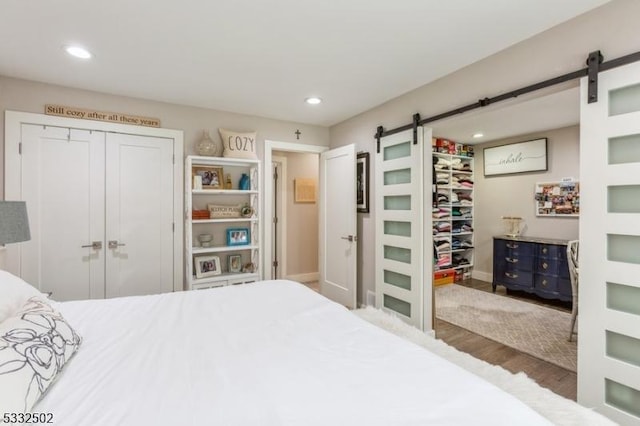 bedroom with a closet, a barn door, and dark hardwood / wood-style floors