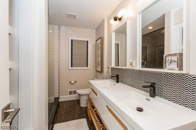 bathroom featuring toilet, walk in shower, vanity, tile patterned floors, and tasteful backsplash