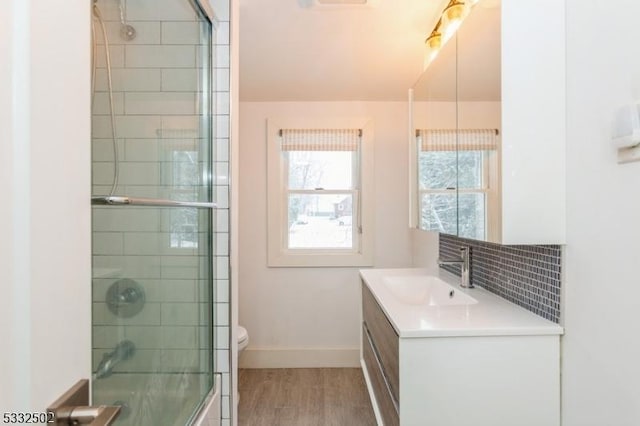 bathroom featuring toilet, vanity, a shower with door, hardwood / wood-style flooring, and backsplash