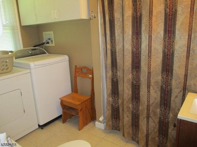 laundry room with independent washer and dryer and light tile patterned floors