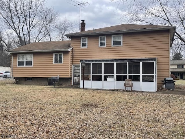 rear view of house with a sunroom and a yard