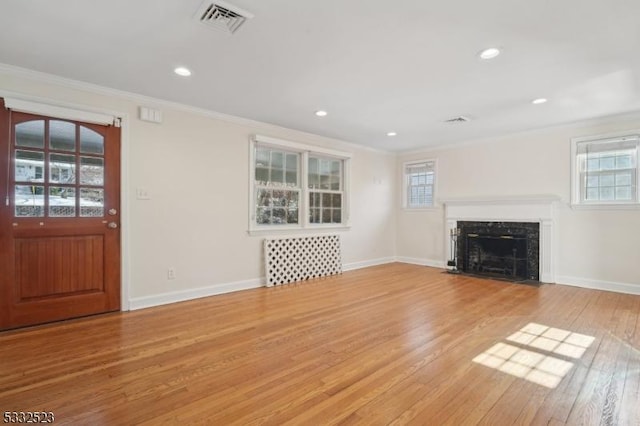 unfurnished living room featuring crown molding, plenty of natural light, and light wood-type flooring