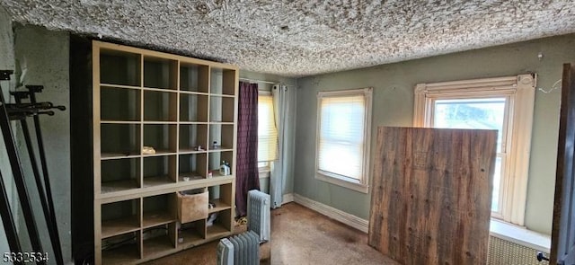 interior space featuring carpet floors, radiator heating unit, and a textured ceiling