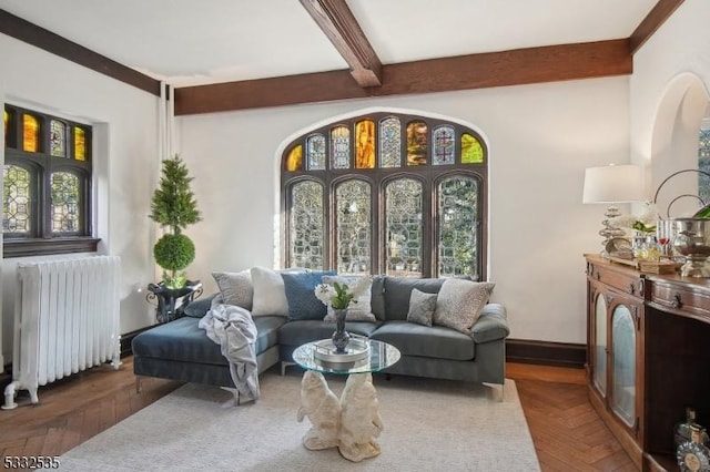 living room with radiator, a wealth of natural light, dark parquet floors, and beamed ceiling