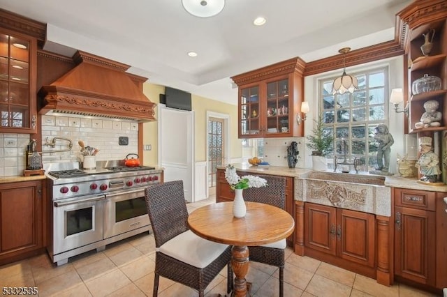 kitchen with pendant lighting, premium range hood, double oven range, light tile patterned flooring, and decorative backsplash