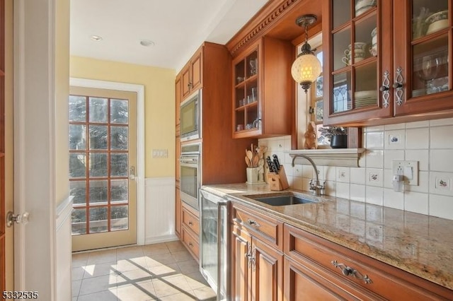 kitchen featuring light tile patterned flooring, sink, light stone counters, hanging light fixtures, and appliances with stainless steel finishes