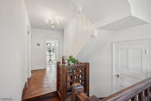 stairway featuring parquet flooring and an inviting chandelier