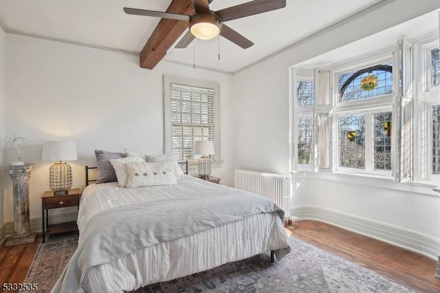 bedroom featuring ceiling fan, radiator heating unit, dark hardwood / wood-style floors, and beam ceiling