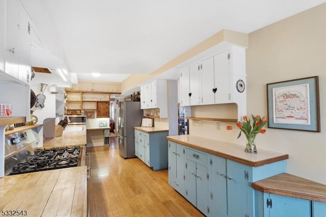 kitchen featuring white cabinets, blue cabinets, stainless steel appliances, and light hardwood / wood-style flooring