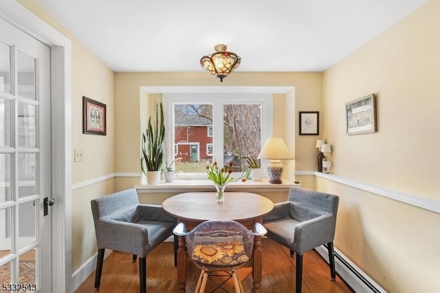 dining space with hardwood / wood-style flooring and a baseboard heating unit