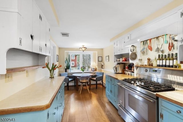 kitchen with high end stove, white cabinetry, blue cabinetry, and dark wood-type flooring