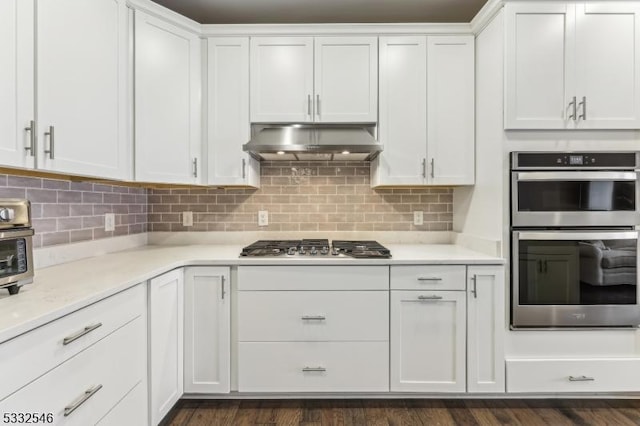 kitchen with appliances with stainless steel finishes, extractor fan, white cabinets, and tasteful backsplash