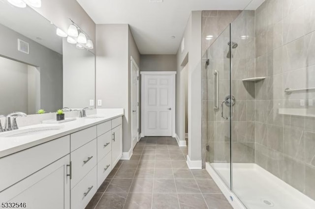 bathroom with a shower with door, tile patterned floors, and vanity