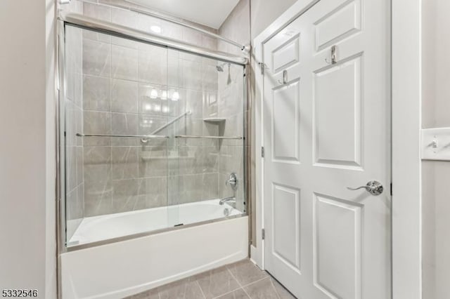 bathroom with bath / shower combo with glass door and tile patterned floors