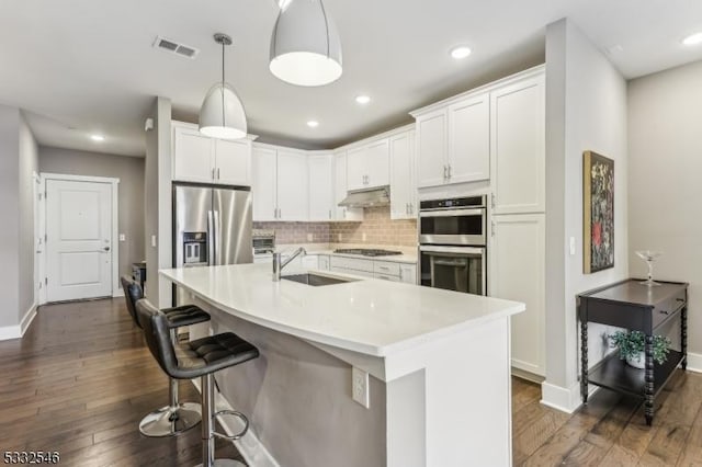 kitchen with appliances with stainless steel finishes, decorative light fixtures, white cabinetry, decorative backsplash, and sink