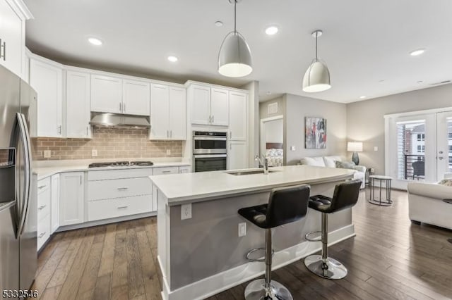 kitchen featuring appliances with stainless steel finishes, pendant lighting, white cabinetry, and sink