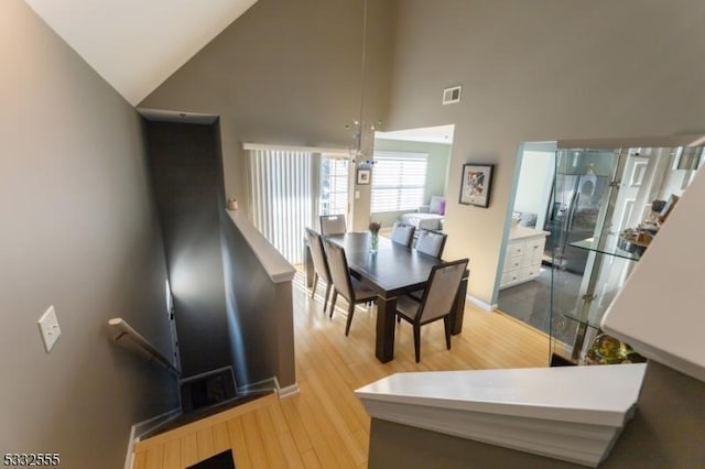 dining space featuring high vaulted ceiling and light hardwood / wood-style floors