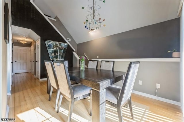 dining room featuring lofted ceiling, a notable chandelier, and light wood-type flooring