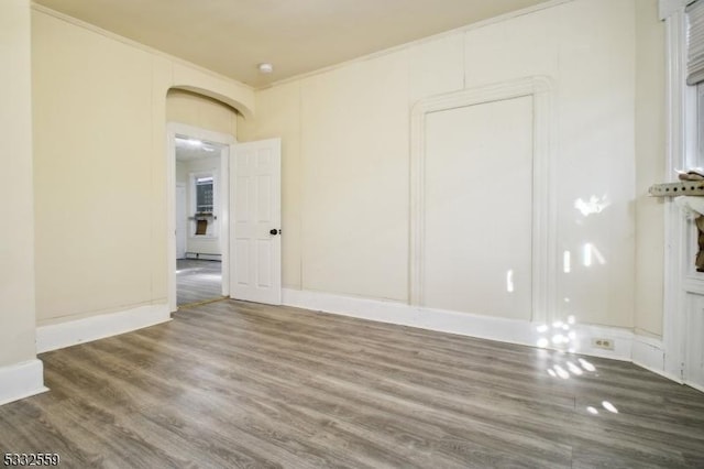 empty room with hardwood / wood-style flooring and crown molding