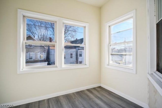 spare room with dark wood-type flooring and a healthy amount of sunlight