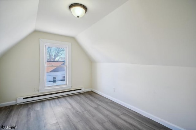 additional living space with light hardwood / wood-style flooring, vaulted ceiling, and a baseboard heating unit