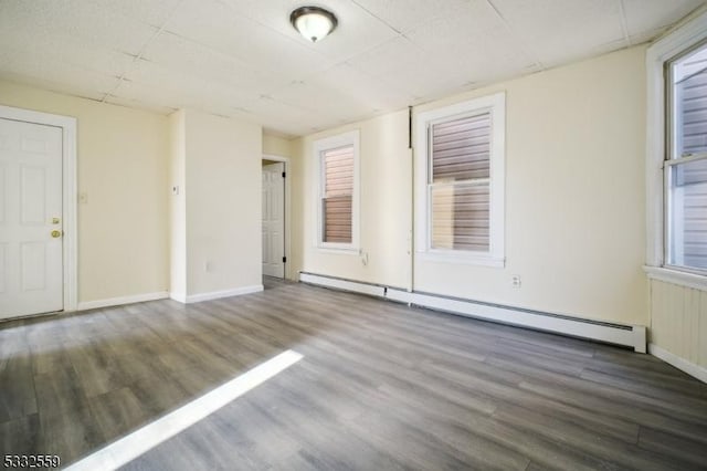 unfurnished room with dark hardwood / wood-style floors and baseboard heating