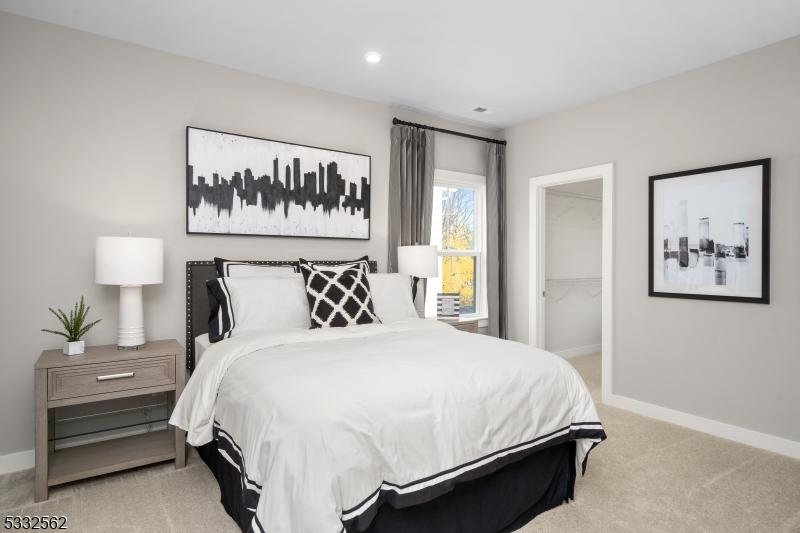 bedroom featuring a walk in closet, light carpet, and a closet