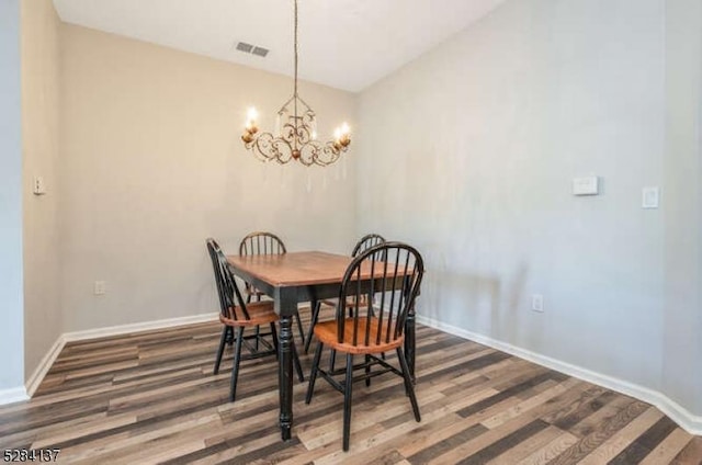 dining room with dark wood-type flooring and a notable chandelier