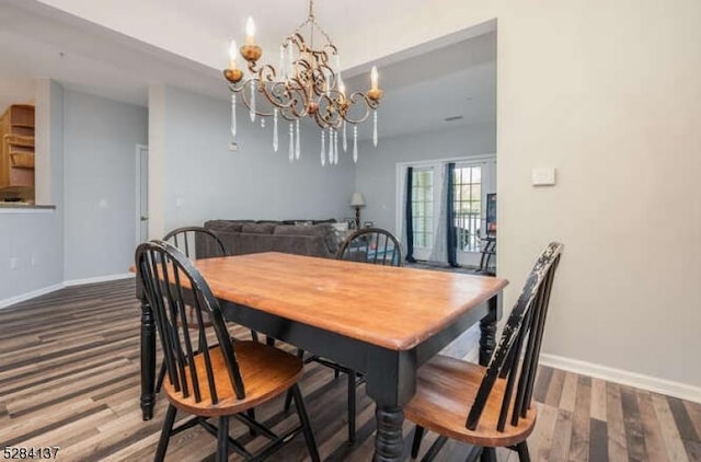 dining area with wood-type flooring and an inviting chandelier