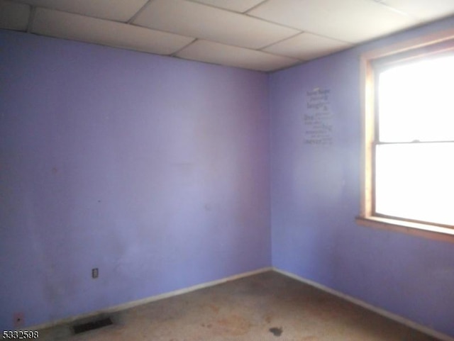 carpeted spare room featuring a drop ceiling